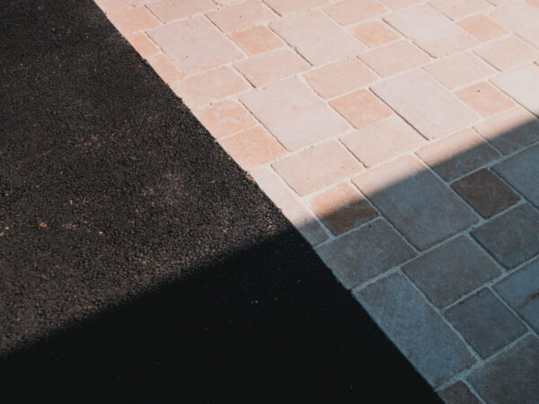 Création d’un aménagement extérieur autour d’une maison moderne à Ploudaniel avec allée en enrobé noir, cheminements en pavés, dallage en schiste et intégration paysagère soignée.